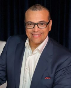 Man in glasses blue blazer white shirt.